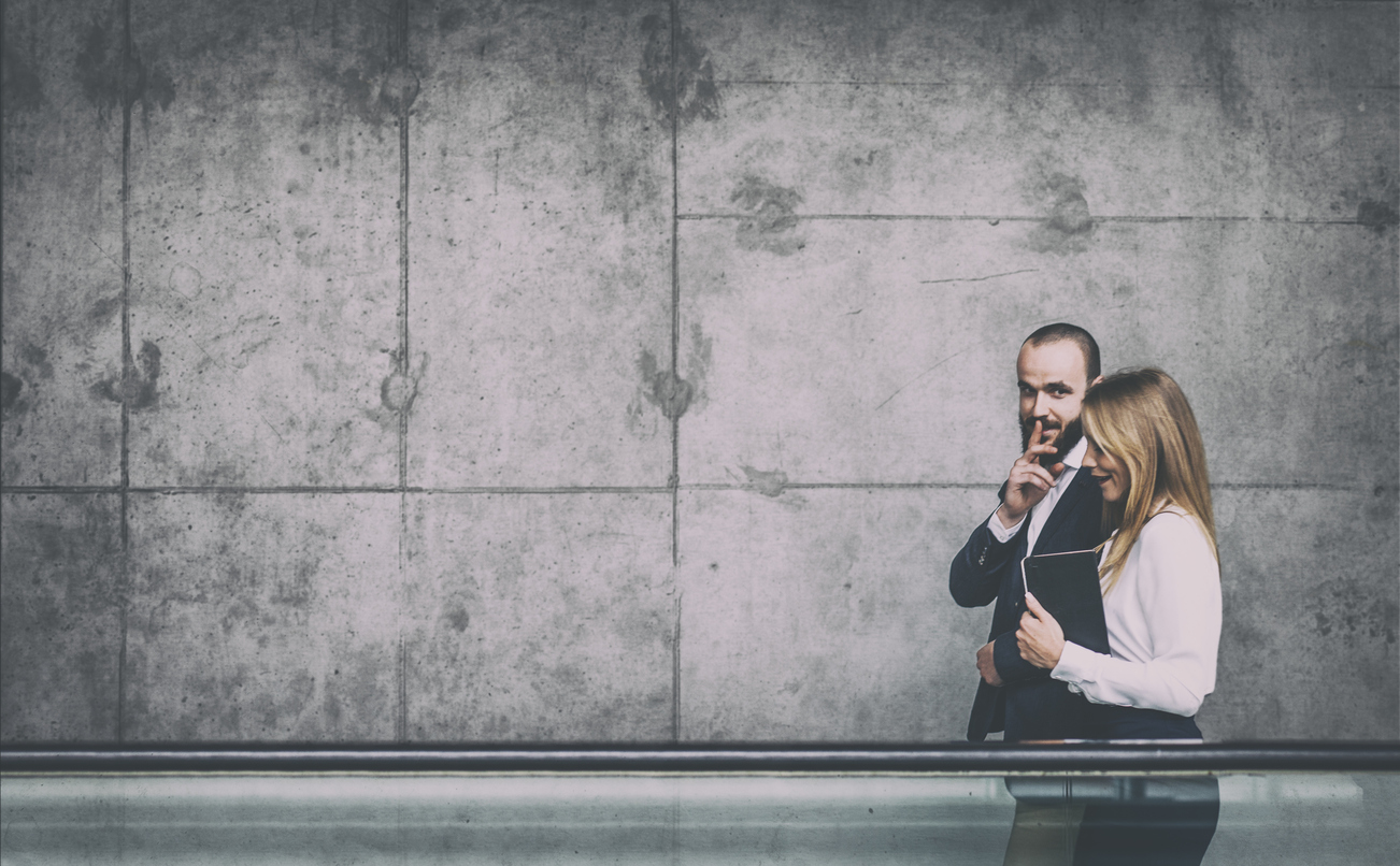 Businessman and businesswoman walking and sharing office rumors